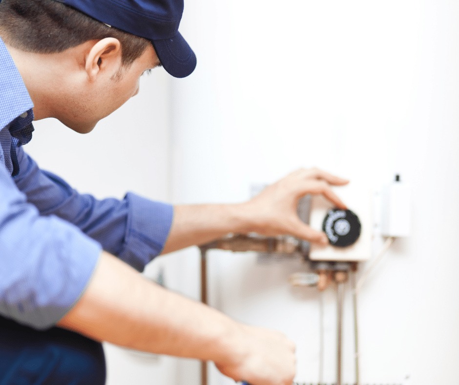 A plumber adjusting a water heater.