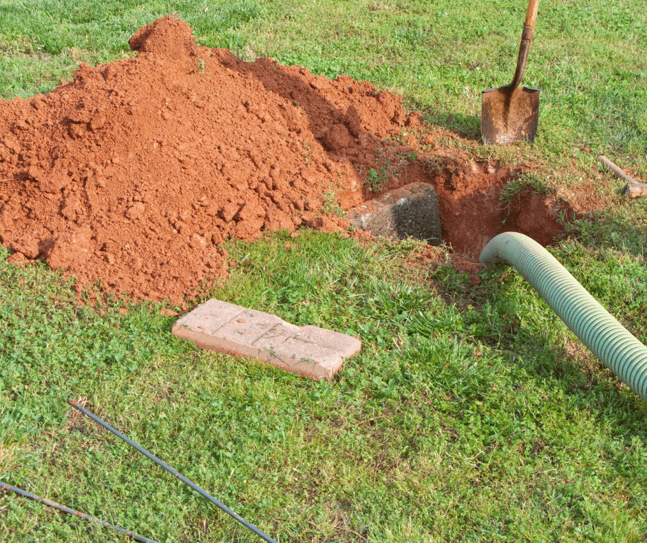 A septic tank site has a hose running to it to remove the waste